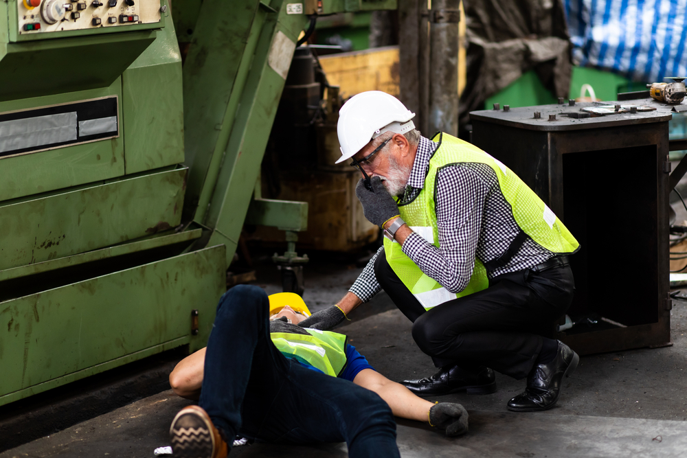 engineering supervisor talking on walkie talkie communication while his coworker lying unconscious at industrial factory