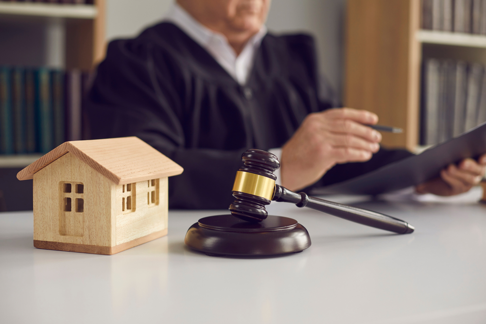 close-up of judge's gavel, sound block, and small wooden toy house on courtroom table in court