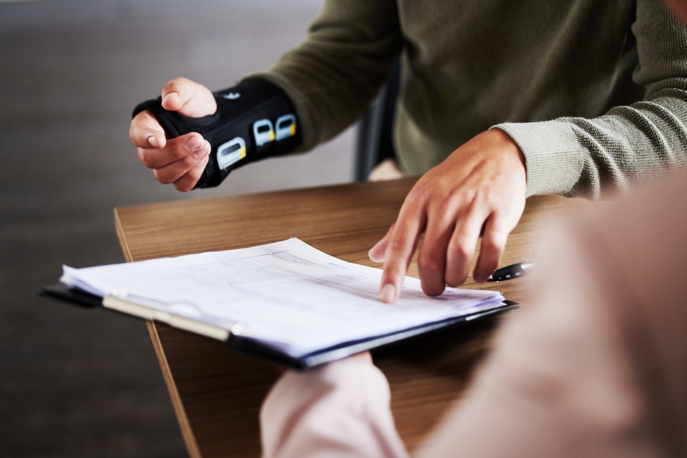 injury, compensation and man hands with insurance documents, legal contract and paperwork