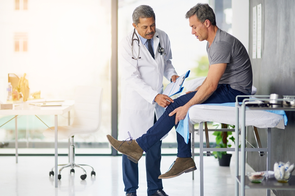 shot of a mature doctor examining his patient who is concerned about his knee