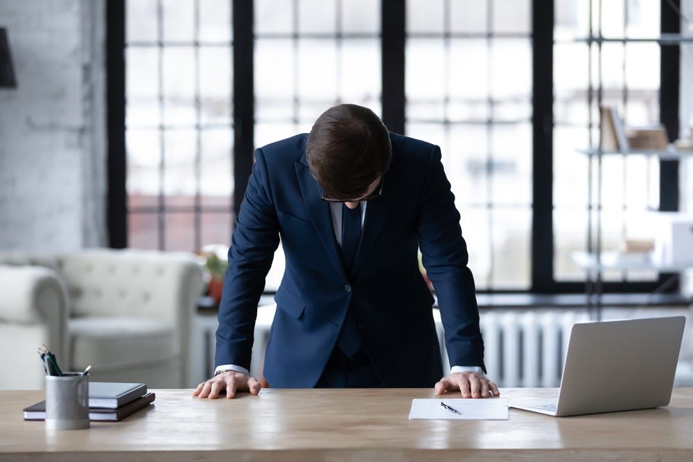 Upset unsuccessful Caucasian businessman stand at desk in office feel stressed after business startup failure