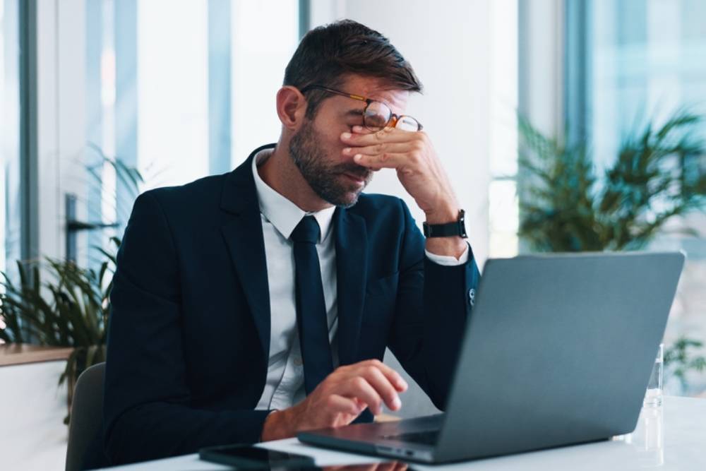 Frustrated, businessman or headache with laptop for stress, mistake or corporate bankruptcy at office