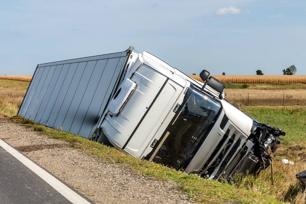 The large truck lies in a side ditch after the road accident.